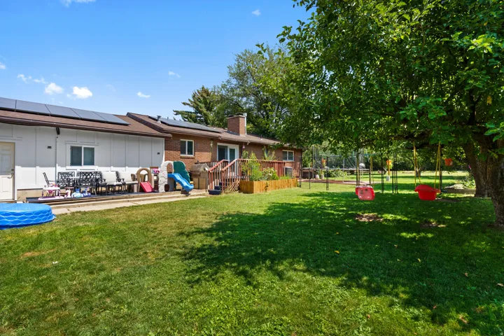 Expansive backyard with a manicured lawn, mature trees, fruit trees.