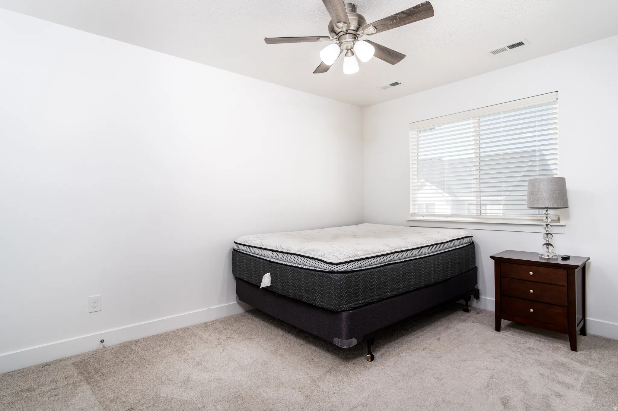 Carpeted room with a ceiling fan featuring integrated lighting, a window with horizontal blinds, and white walls