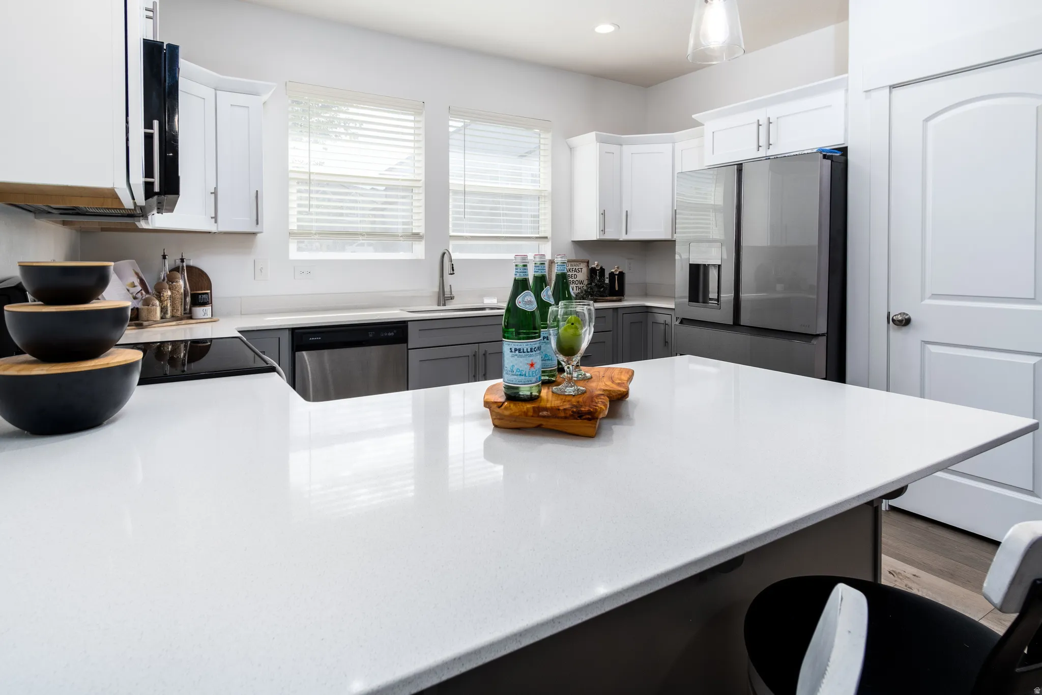 Spacious kitchen island with light-toned countertop, complemented by two-tone cabinetry featuring white upper and grey lower units
