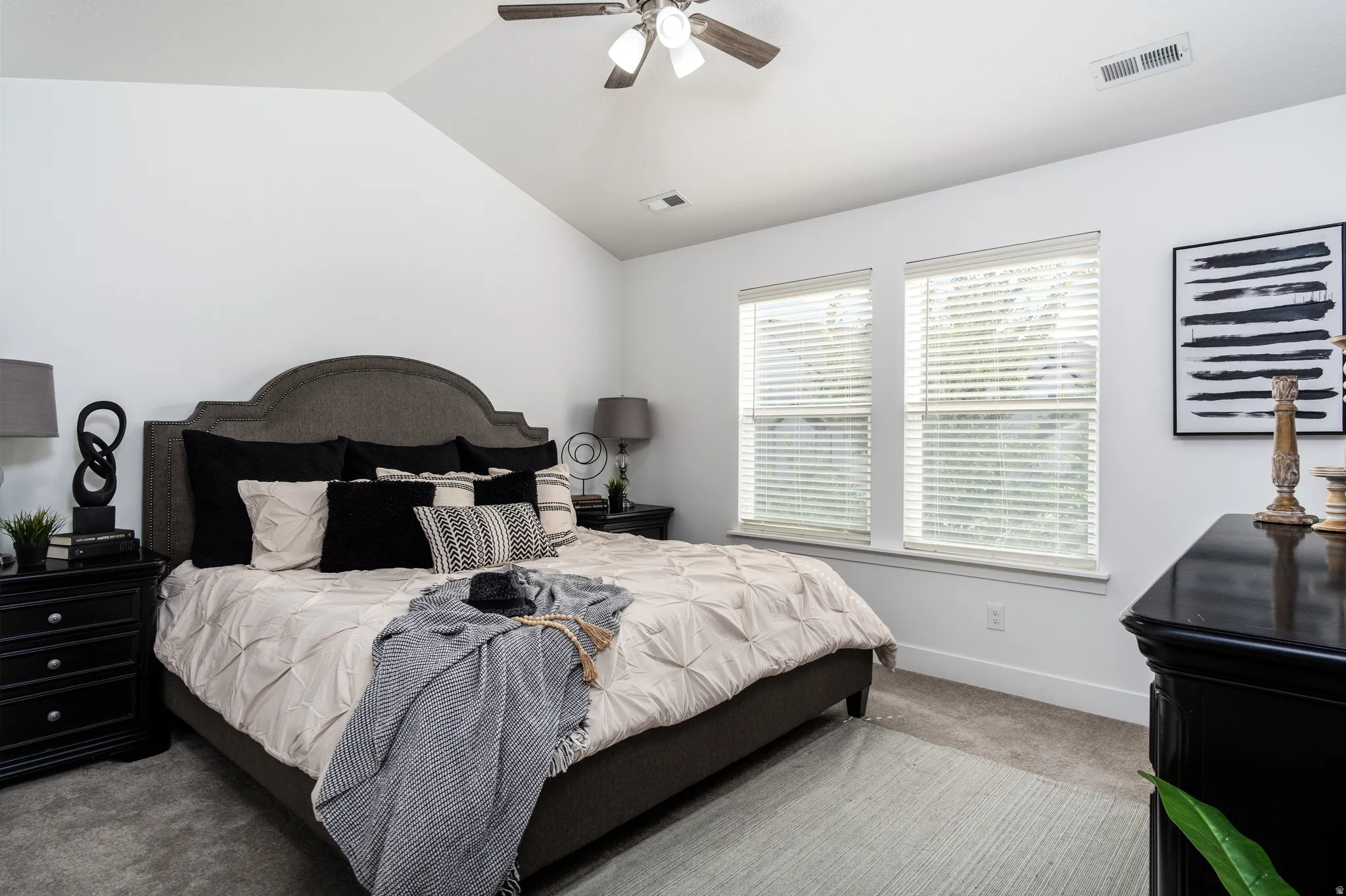 Bedroom featuring a vaulted ceiling with a ceiling fan, dual windows with blinds, and carpet flooring