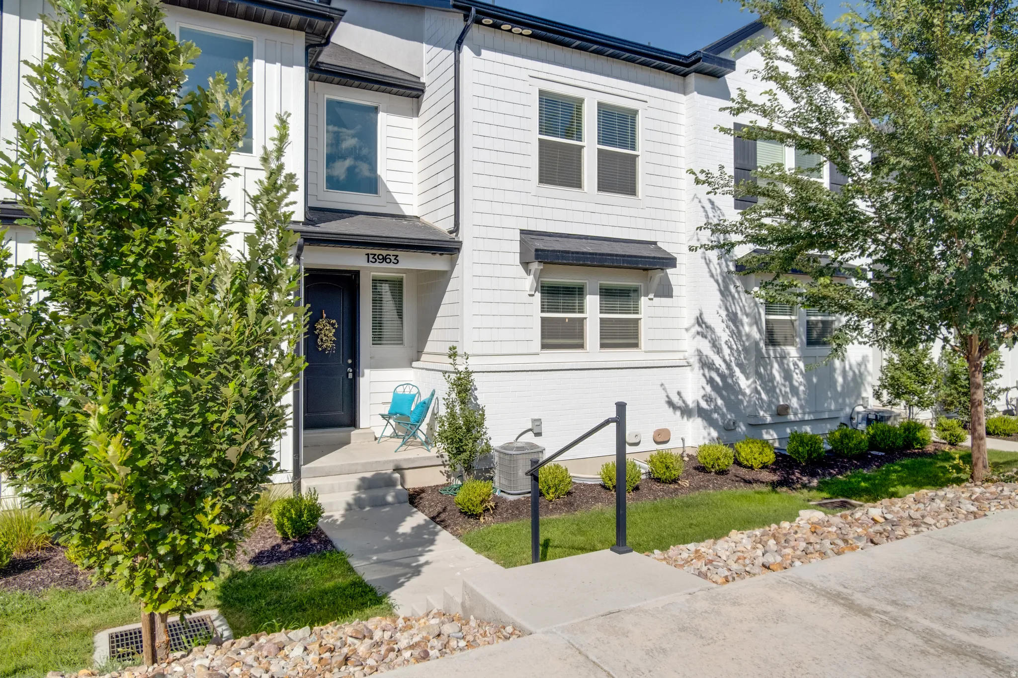 White multi-level townhouse with a dark entry door and prominent street number
