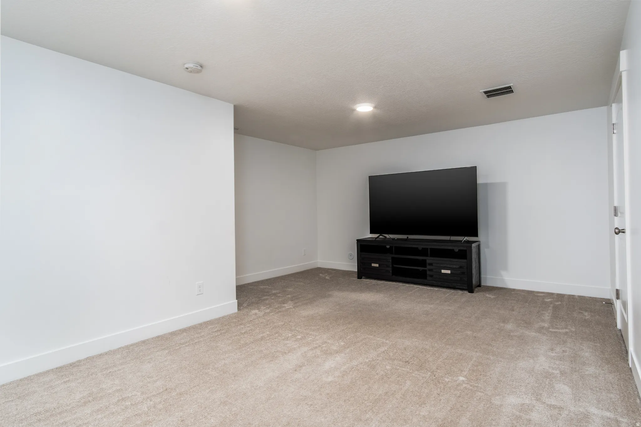 Carpeted room with white walls, recessed lighting, and a white interior door