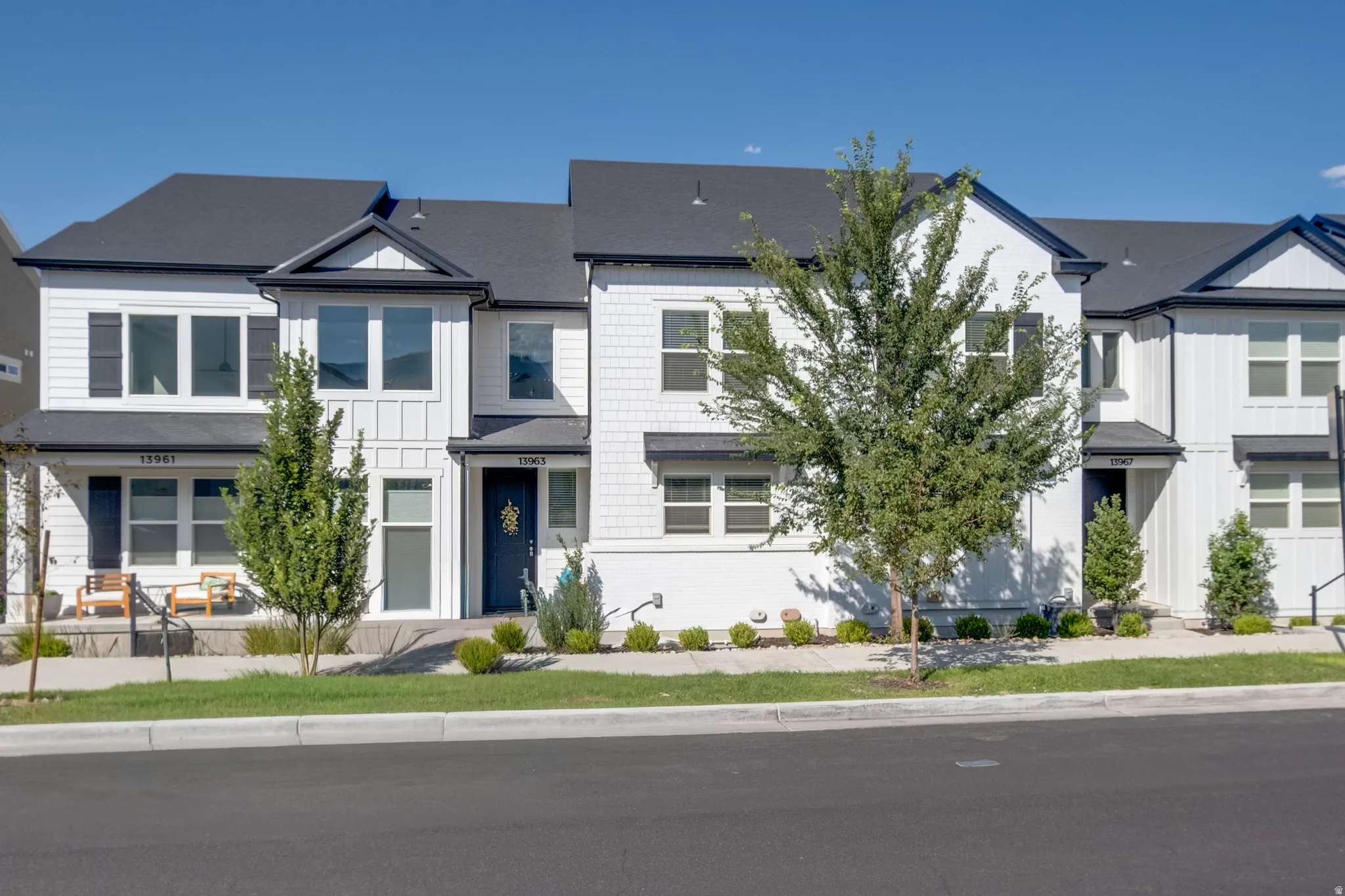 Modern townhome exterior featuring white siding with black trim, a dark asphalt shingle roof, and a welcoming front entrance