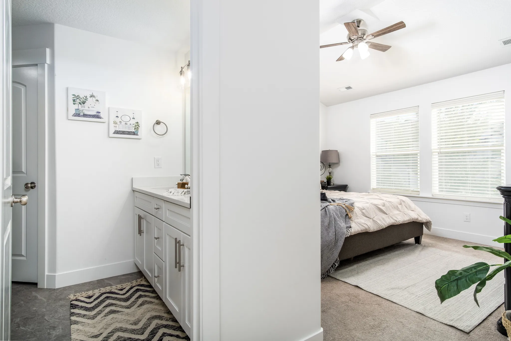 White vanity with shaker-style cabinetry, a light-toned countertop, and a contemporary wall-mounted light fixture
