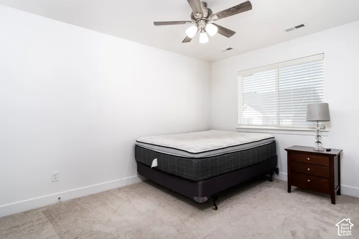 Carpeted room with a ceiling fan featuring integrated lighting, a window with horizontal blinds, and white walls