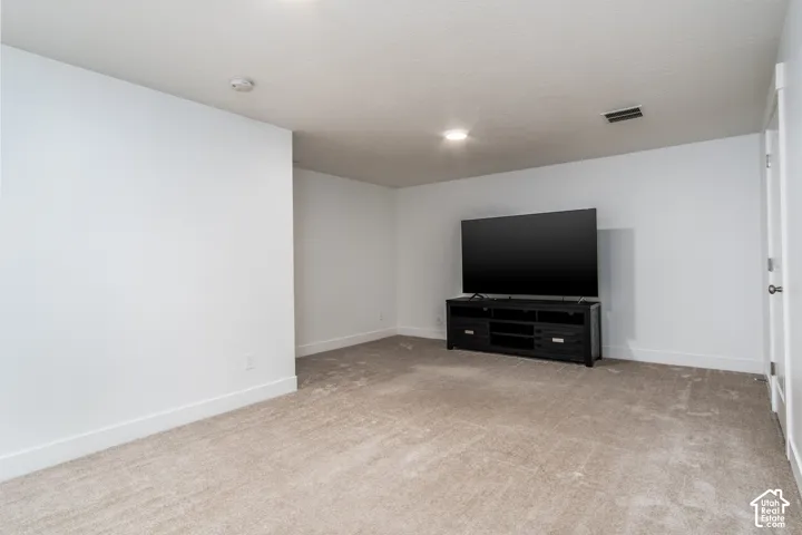 Carpeted room with white walls, recessed lighting, and a white interior door