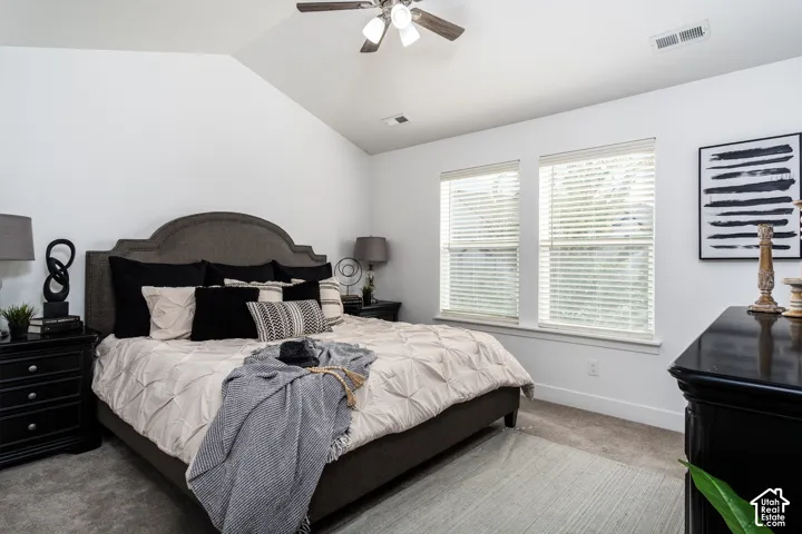 Bedroom featuring a vaulted ceiling with a ceiling fan, dual windows with blinds, and carpet flooring