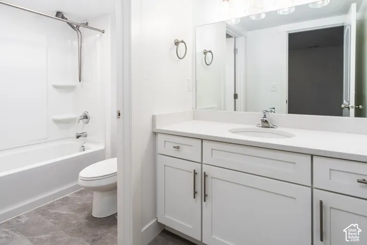 Bathroom featuring a white vanity with an integrated sink, polished chrome faucet, and a large mirror with overhead lighting