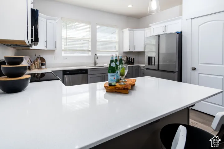 Spacious kitchen island with light-toned countertop, complemented by two-tone cabinetry featuring white upper and grey lower units