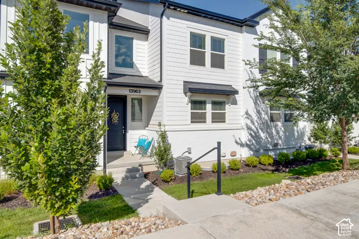 White multi-level townhouse with a dark entry door and prominent street number