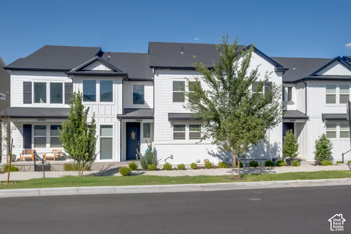Modern townhome exterior featuring white siding with black trim, a dark asphalt shingle roof, and a welcoming front entrance
