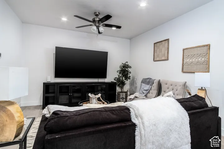 Living area featuring light wood-finish flooring, recessed ceiling lighting, and a ceiling fan with light fixture