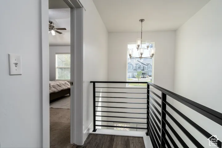 Upper landing featuring a contemporary chandelier, horizontal metal stair railing, and wood-finish flooring
