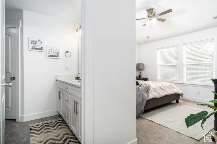 White vanity with shaker-style cabinetry, a light-toned countertop, and a contemporary wall-mounted light fixture