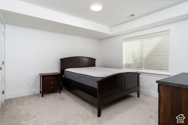 Bedroom featuring a window with horizontal blinds, overhead flush mount lighting, and light-colored carpeting