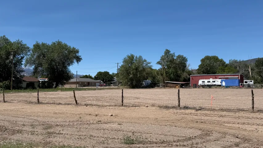 Expansive undeveloped lot featuring a partial wire fence and mature trees along the perimeter