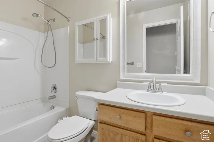Bathroom featuring a single vanity with wood cabinetry, a white countertop, an integrated sink, a mirrored medicine cabinet, and a white tub/shower combination