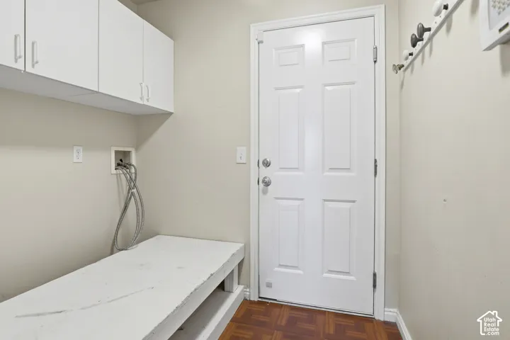 Laundry area featuring overhead white cabinetry, a utility sink connection, and wood-finish flooring