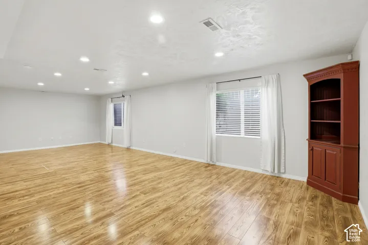 Recessed ceiling lighting, wood-finish flooring, white window blinds, and built-in shelving