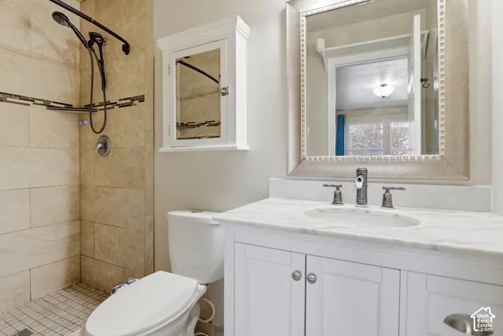 White vanity with a stone countertop, an undermount sink, and a framed mirror