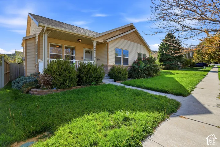 Exterior featuring a covered front porch, light-toned siding, and stone accents