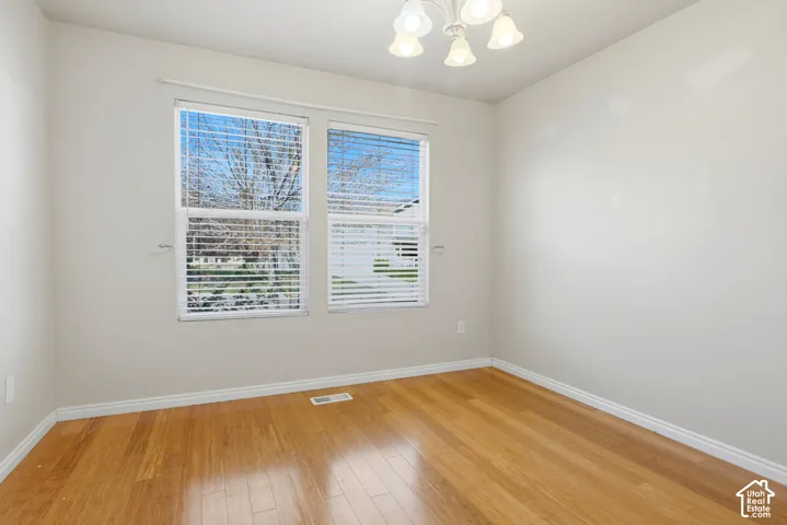 Hardwood flooring, two windows with blinds, white trim, and a ceiling-mounted light fixture
