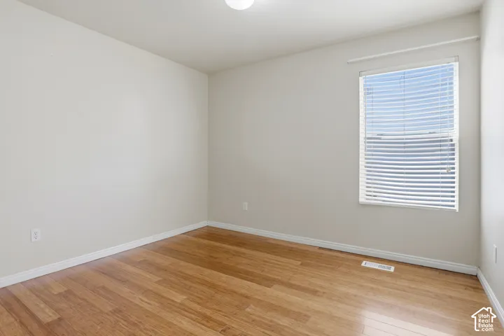 Wood-finish flooring, neutral wall tones, window with horizontal blinds, and a ceiling-mounted light fixture