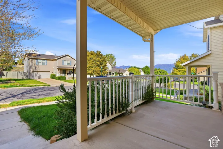Covered concrete porch with white spindle railing and mountain backdrop