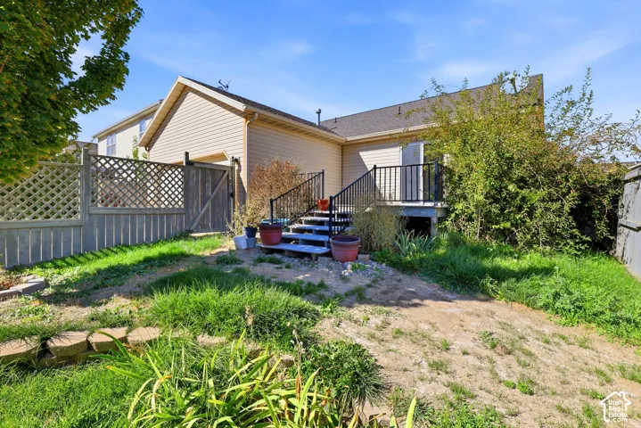 Rear exterior with a wood lattice fence, private yard gate, and second-story deck with black railings