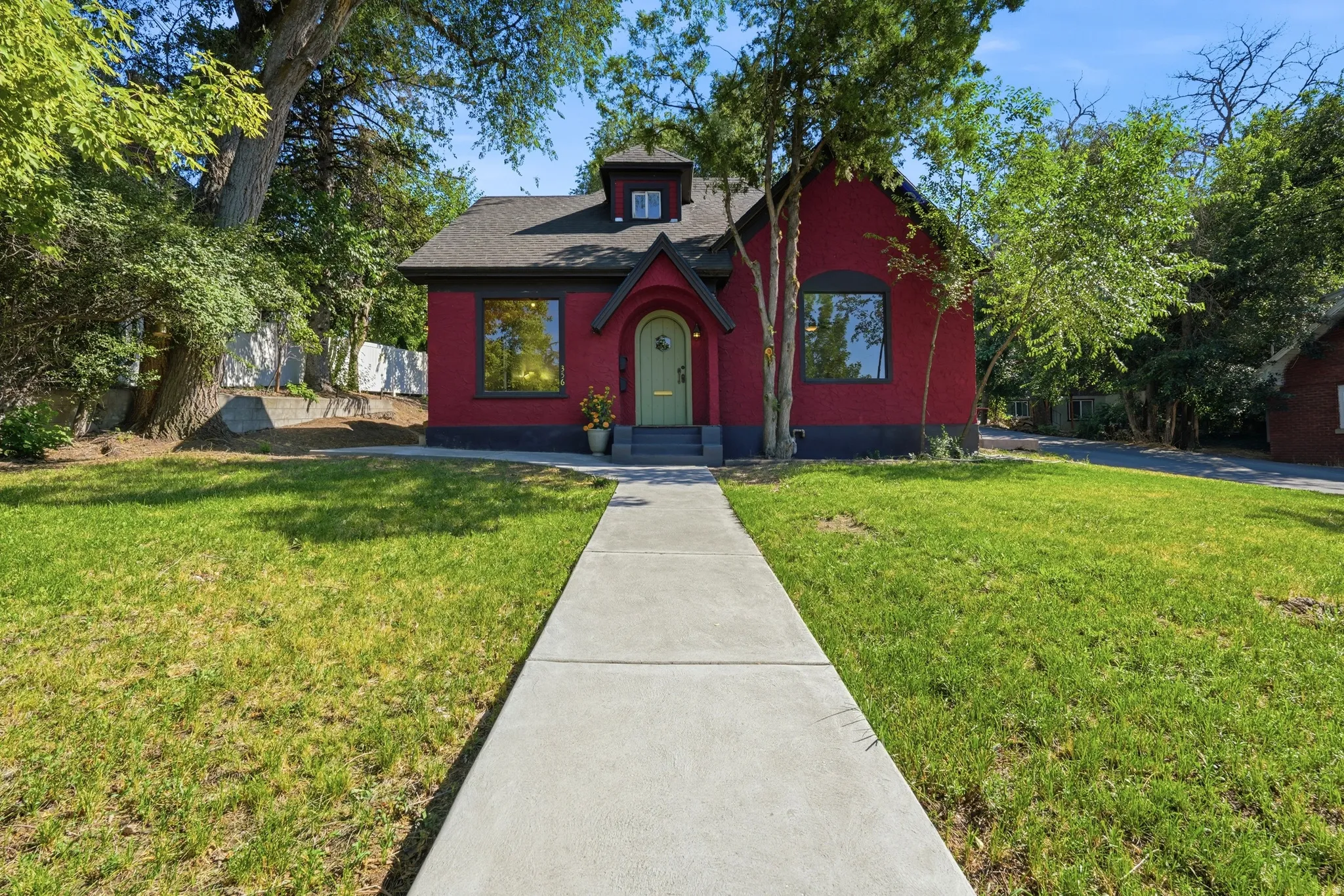 Red exterior with a light green arched entry door, dark trim, and a dormer window