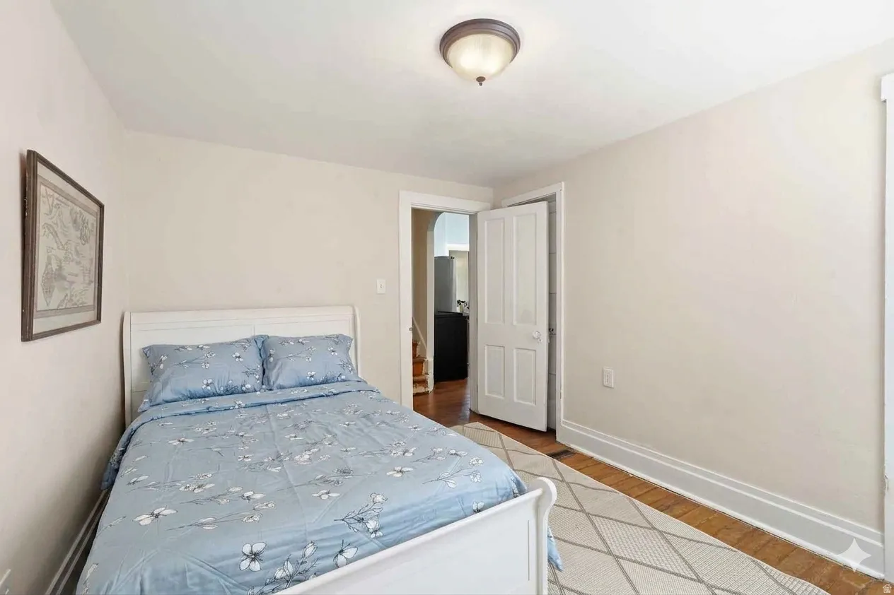 Bedroom featuring light-toned walls, wood-finish flooring, and white baseboards