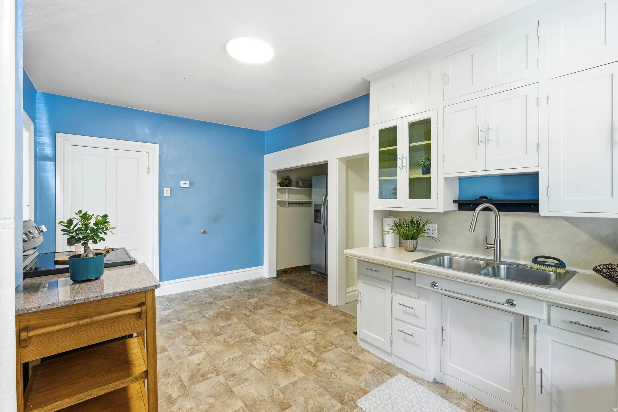 Kitchen featuring white cabinetry, a dual basin stainless steel sink with a modern faucet, and light-toned flooring