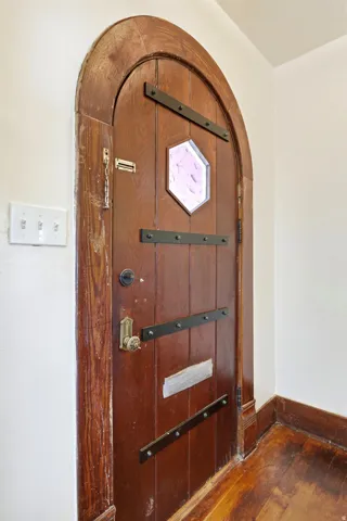 Arched wooden door with decorative metal strapping and an octagonal stained glass inset