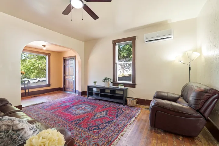 Living area featuring wood-finish flooring, an arched doorway, and a ceiling fan