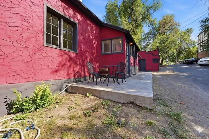 Exterior featuring a red textured stucco finish, dark trim windows, and a concrete patio