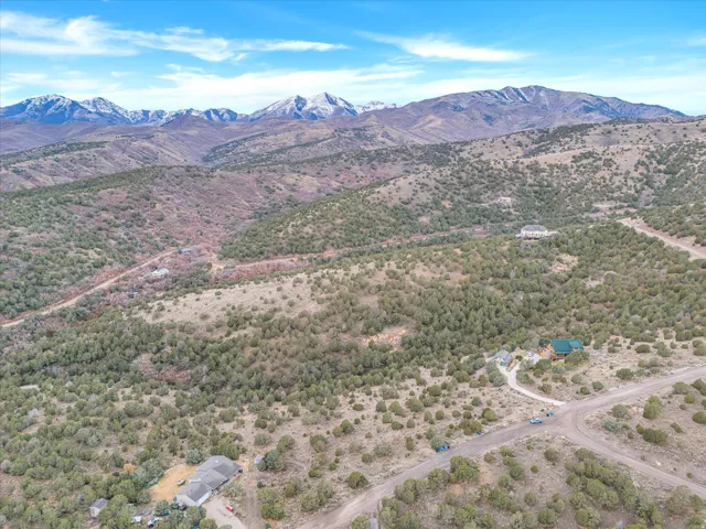 Expansive rural landscape featuring a mountainous backdrop, scattered trees, and visible residential properties