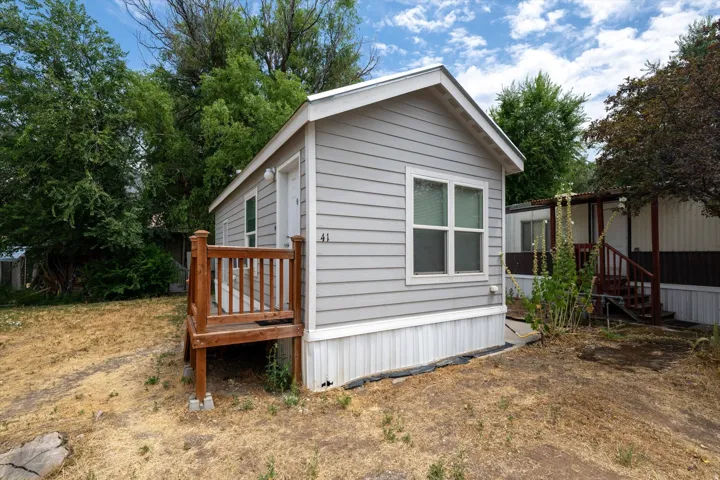 Compact residence featuring light gray horizontal siding and white trim