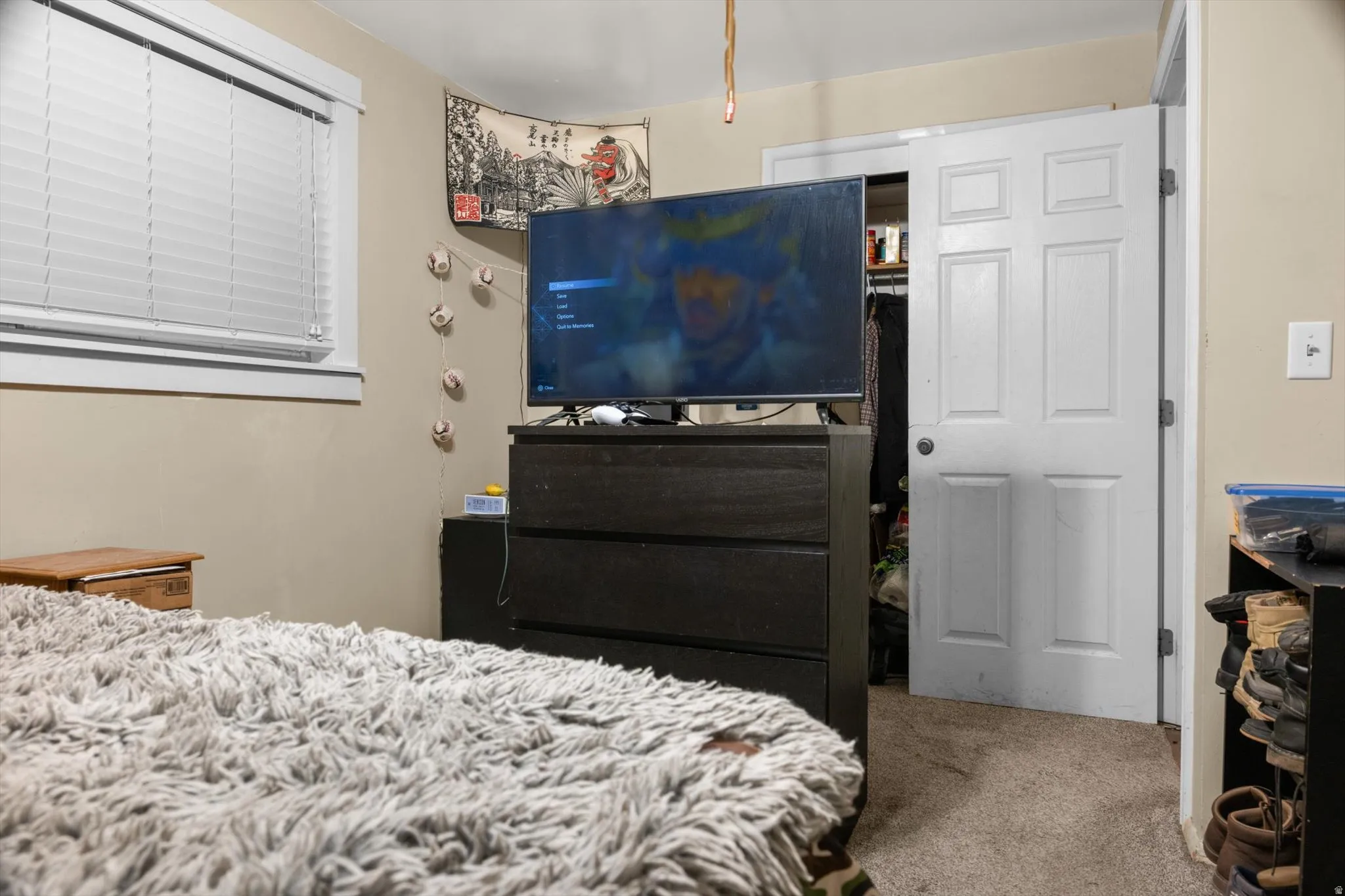 Bedroom featuring neutral wall paint, carpet flooring, a window with horizontal blinds, and a white paneled door