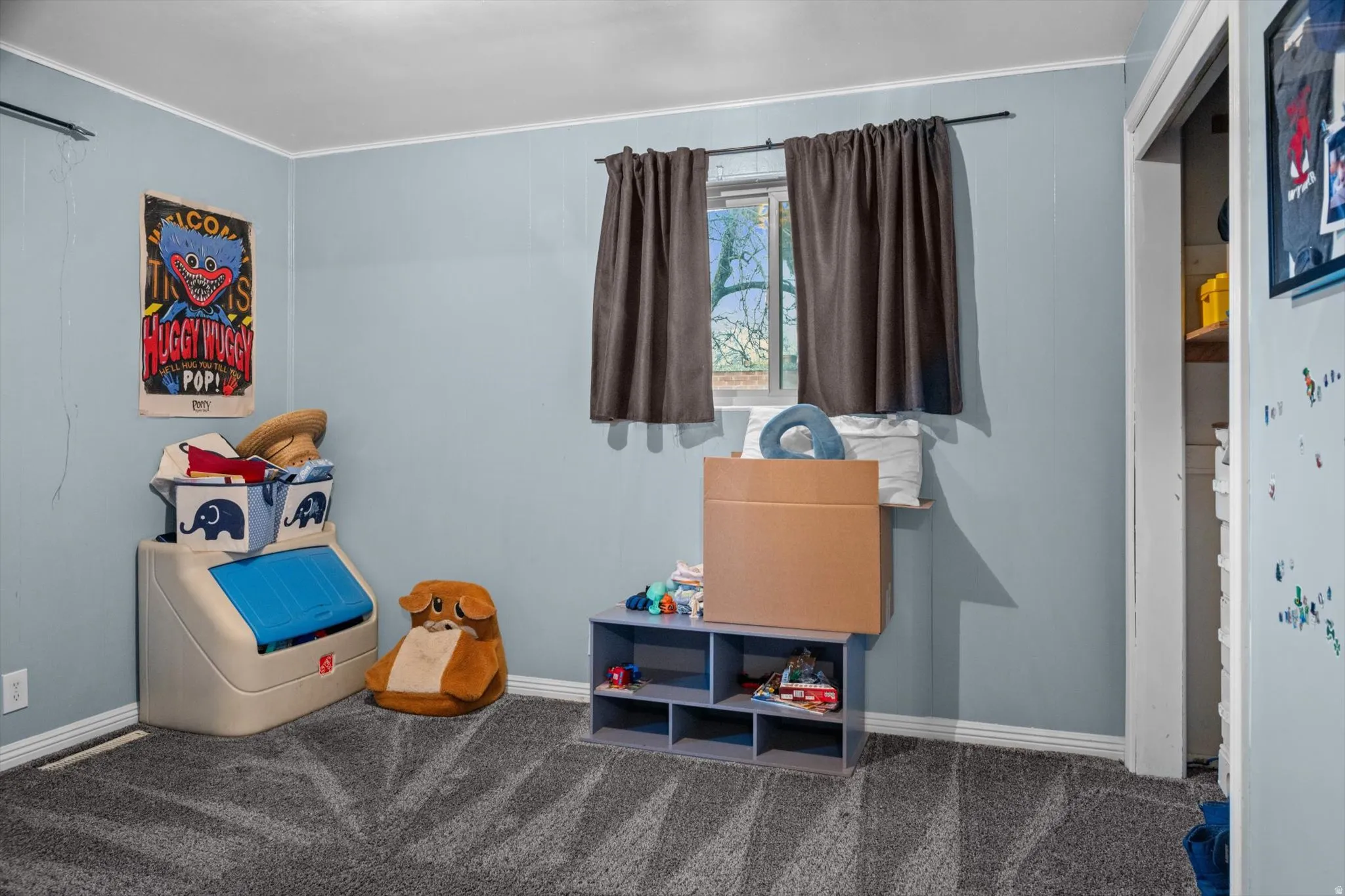 Windowed interior space featuring light blue walls, gray patterned carpeting, and white baseboards