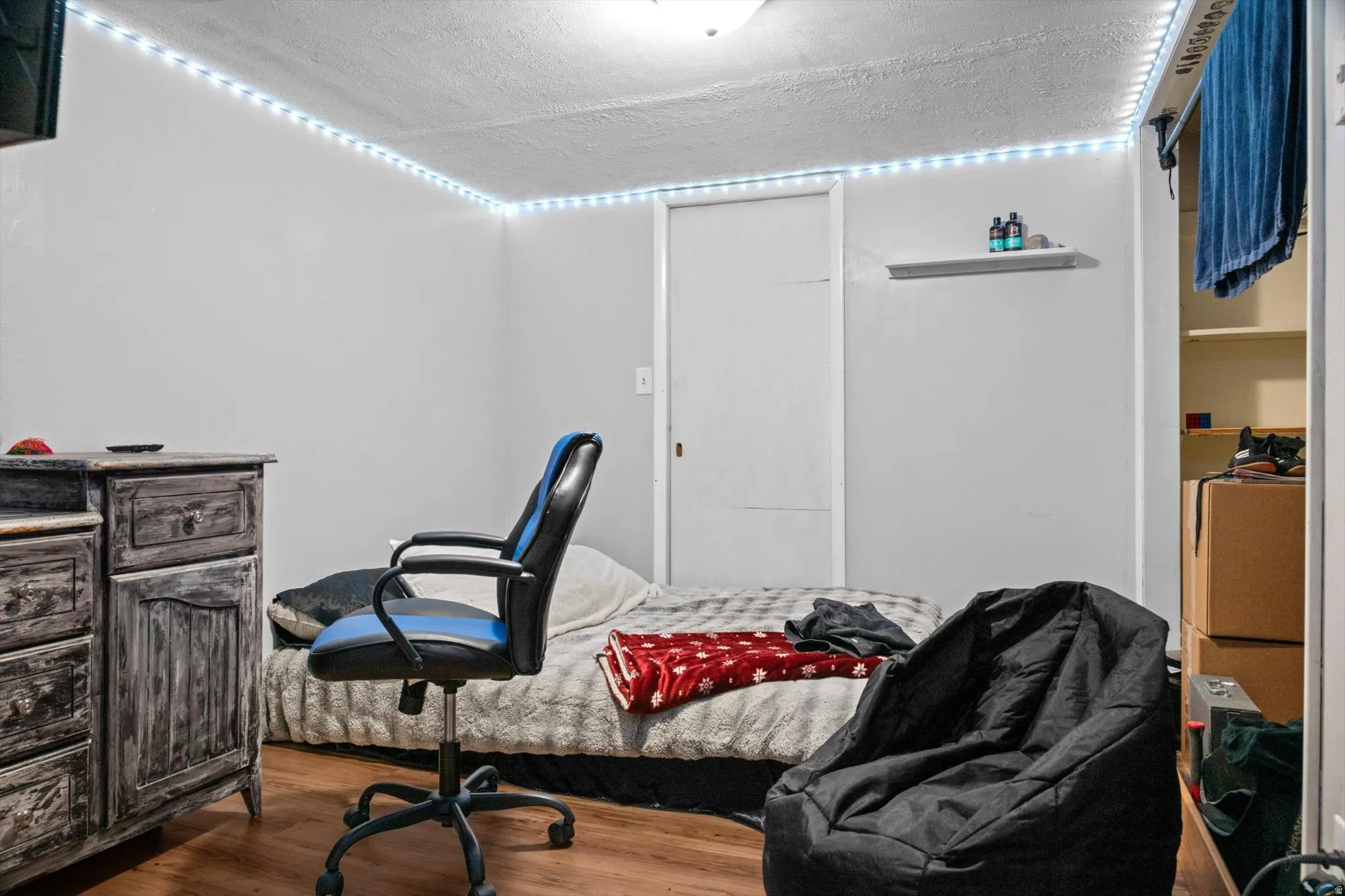 Interior room featuring wood-finish flooring, white painted walls, and a built-in wall shelf
