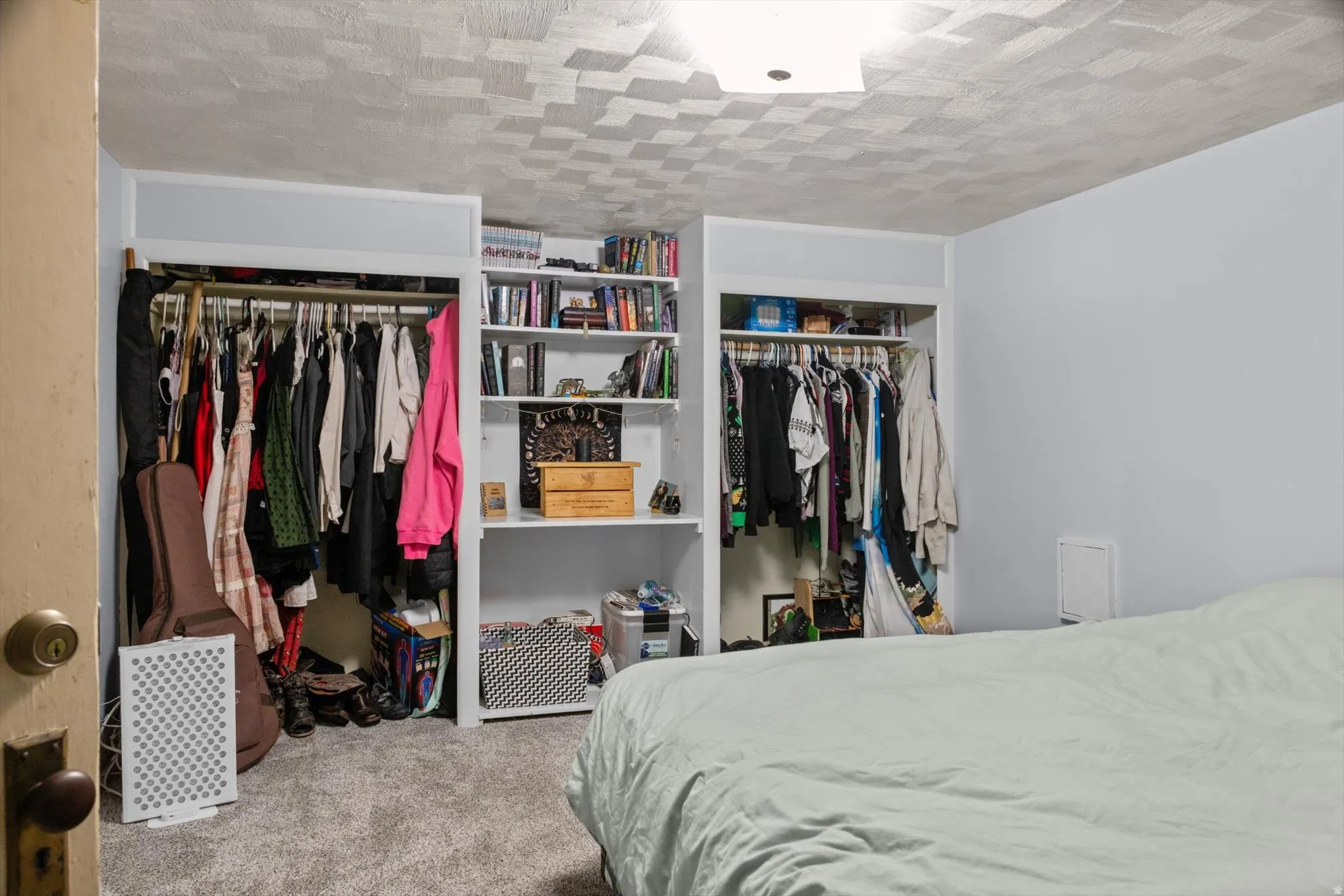 Bedroom featuring built-in shelving, two open closet spaces, and carpet flooring