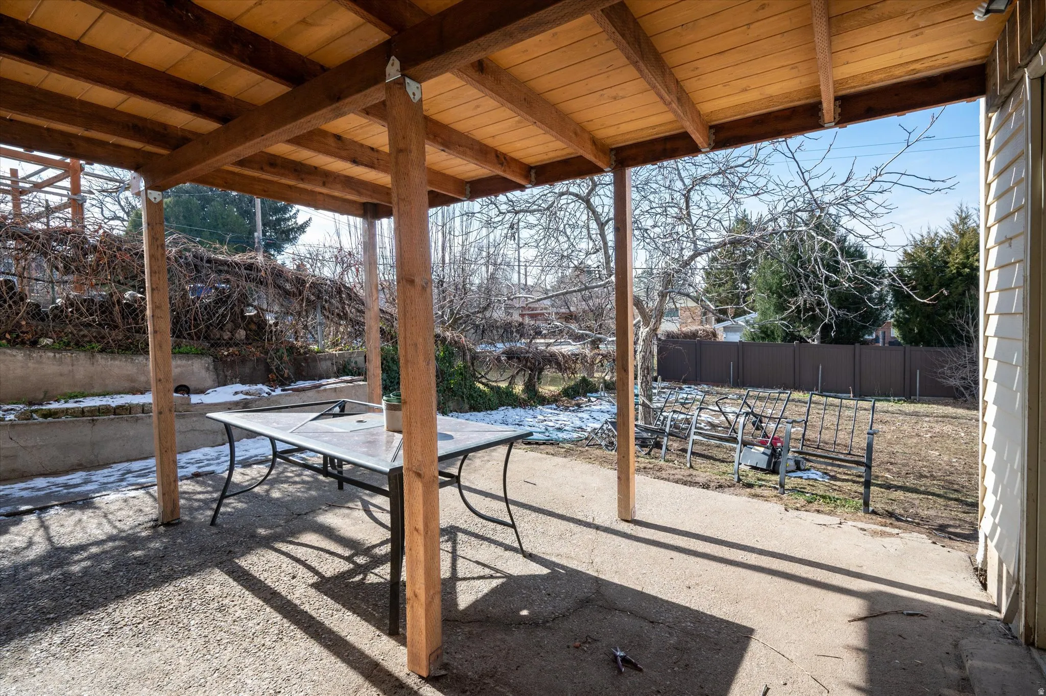 Covered patio space featuring a solid wood ceiling and support beams