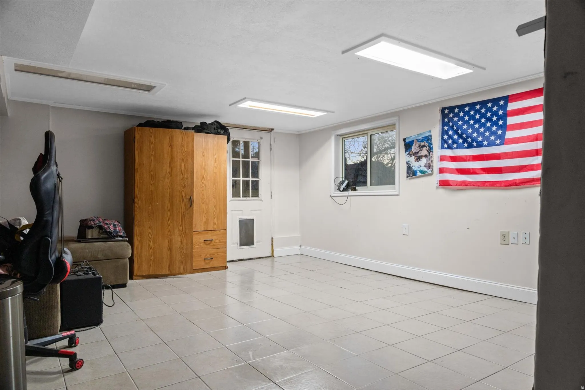 Interior room featuring light-toned tile flooring and white baseboards