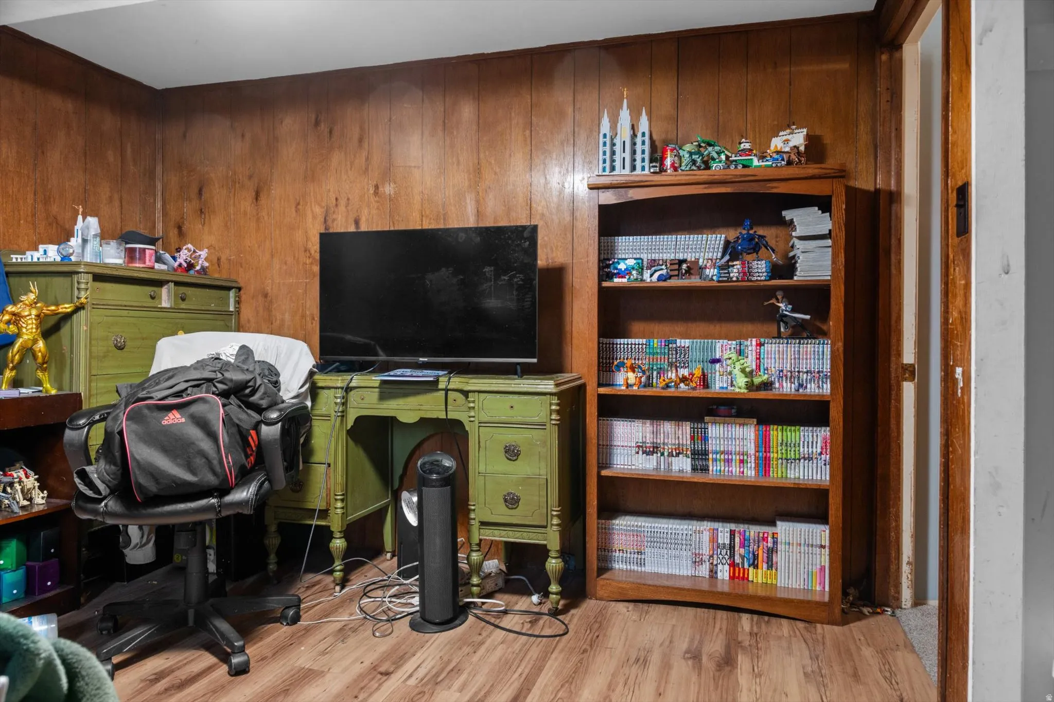 Wood-paneled walls surround a room featuring wood-finish flooring