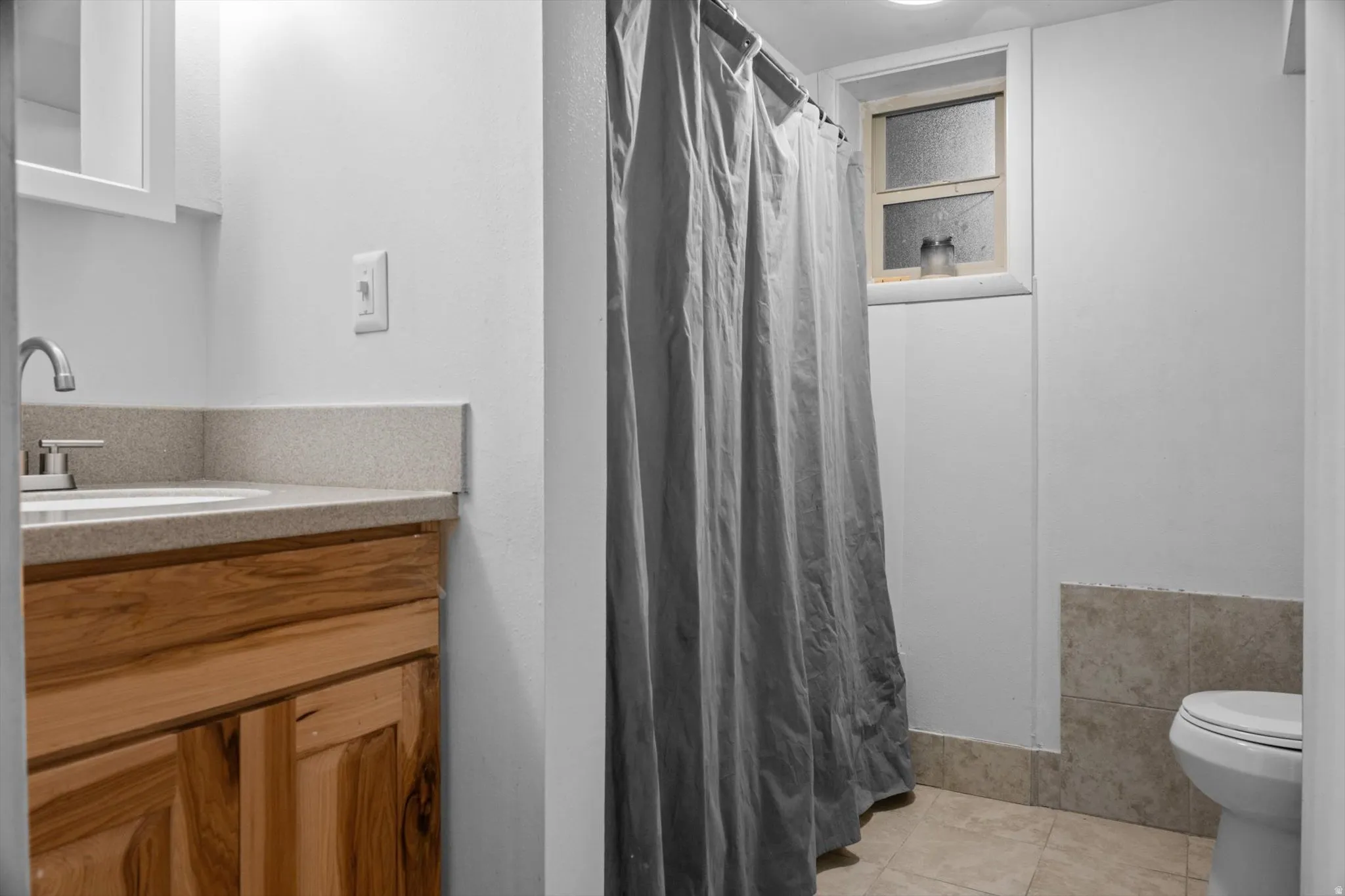 Bathroom featuring a natural wood-finish vanity with a light speckled countertop and undermount sink