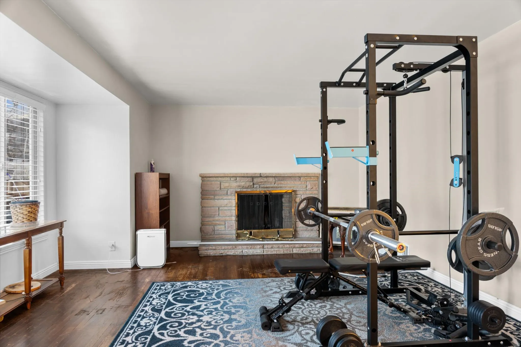 Spacious room featuring hardwood flooring, a stone-faced fireplace, and neutral wall tones
