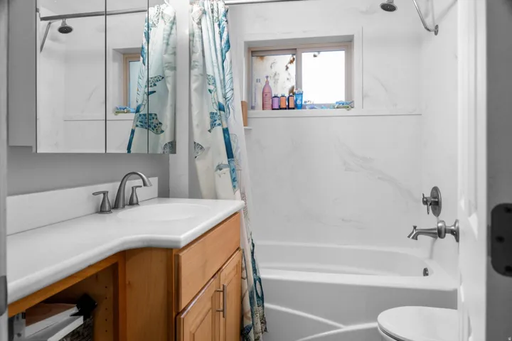 Bathroom featuring a built-in bathtub with a tile-look surround and brushed nickel fixtures