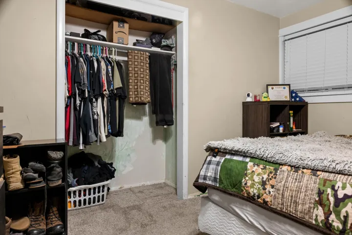 Bedroom featuring neutral painted walls, carpeted flooring, and a window with horizontal blinds