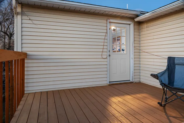 Inviting outdoor deck featuring wood-finish flooring, a coordinating wood railing, and direct access through a paneled door with windowpanes