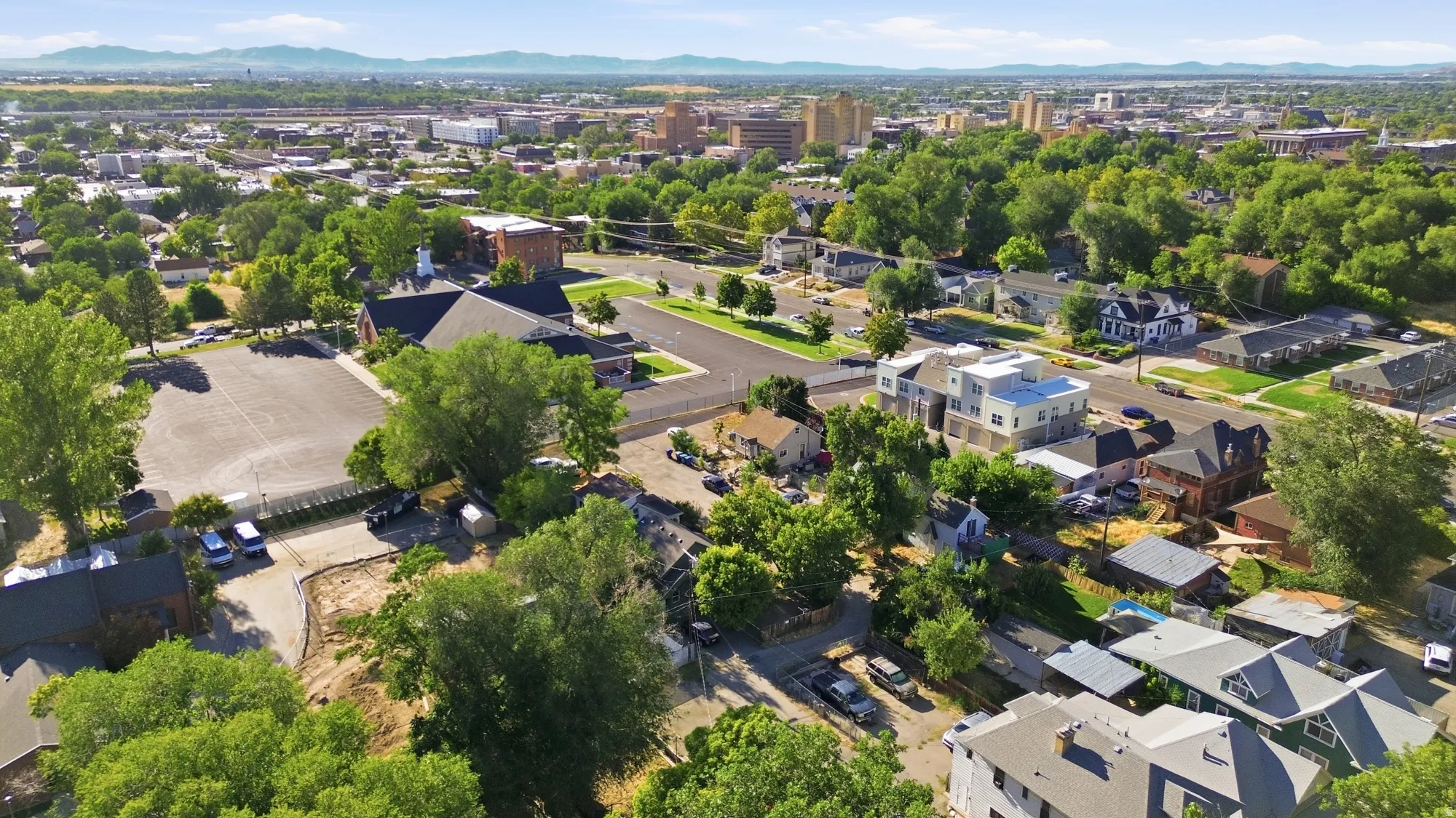 Expansive urban landscape with abundant mature trees and distant mountain ranges